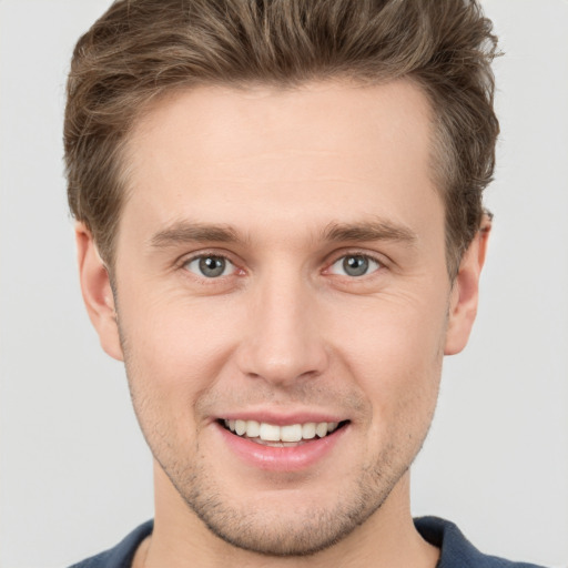 Joyful white young-adult male with short  brown hair and grey eyes