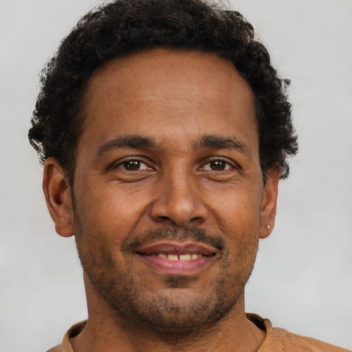 Joyful black adult male with short  brown hair and brown eyes