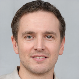 Joyful white young-adult male with short  brown hair and grey eyes