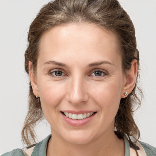 Joyful white young-adult female with medium  brown hair and grey eyes