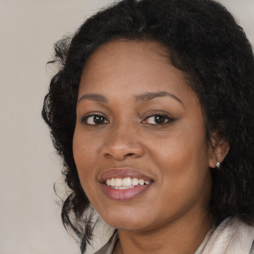 Joyful black young-adult female with long  black hair and brown eyes