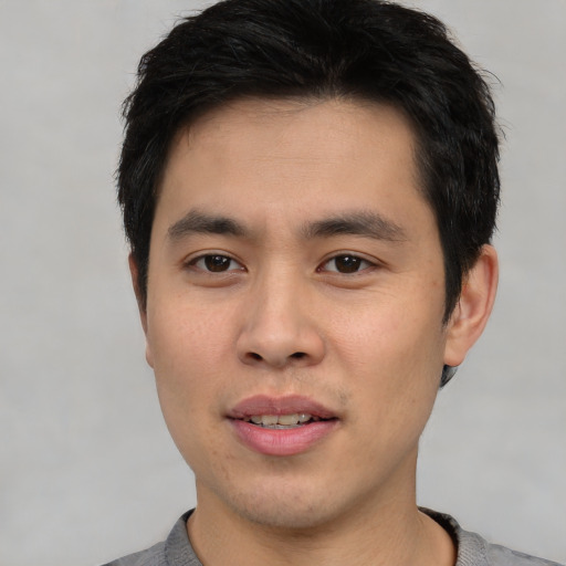 Joyful asian young-adult male with short  black hair and brown eyes