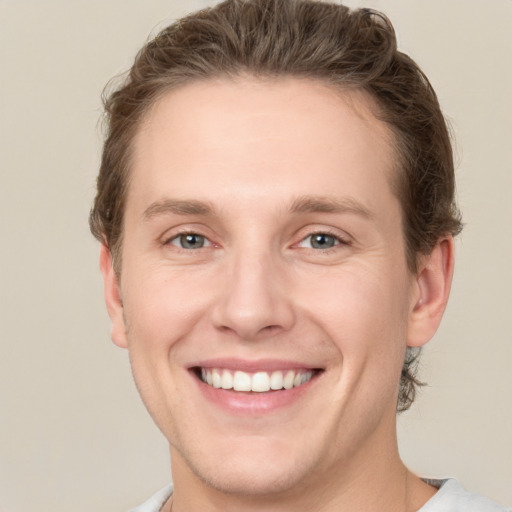 Joyful white young-adult male with short  brown hair and grey eyes