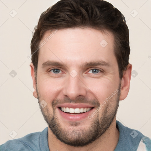 Joyful white young-adult male with short  brown hair and grey eyes