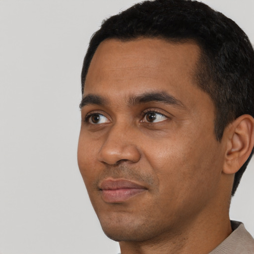 Joyful black young-adult male with short  black hair and brown eyes