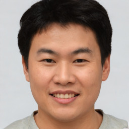 Joyful asian young-adult male with short  brown hair and brown eyes