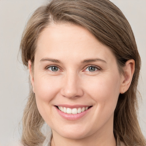 Joyful white young-adult female with medium  brown hair and grey eyes