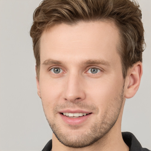 Joyful white young-adult male with short  brown hair and grey eyes