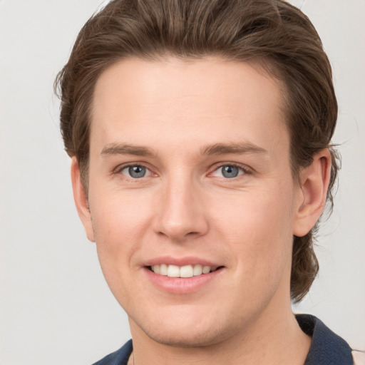 Joyful white young-adult male with short  brown hair and grey eyes