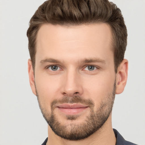 Joyful white young-adult male with short  brown hair and grey eyes