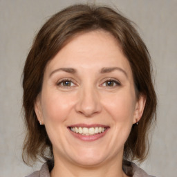 Joyful white adult female with medium  brown hair and grey eyes