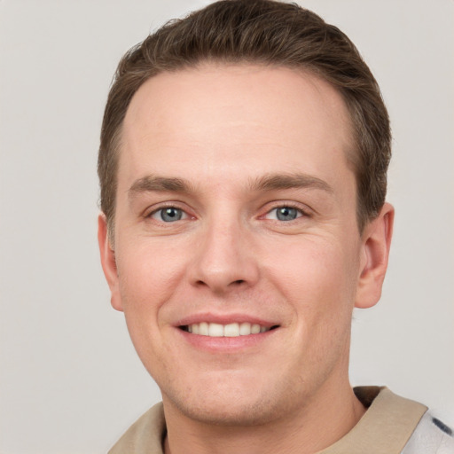 Joyful white young-adult male with short  brown hair and grey eyes