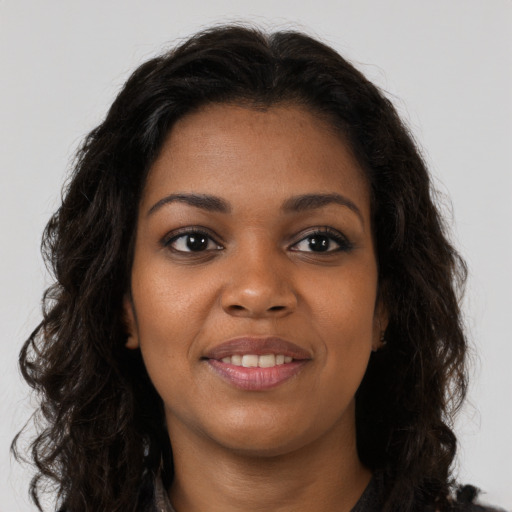Joyful black young-adult female with long  brown hair and brown eyes