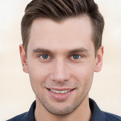 Joyful white young-adult male with short  brown hair and grey eyes