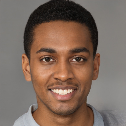 Joyful black young-adult male with short  brown hair and brown eyes