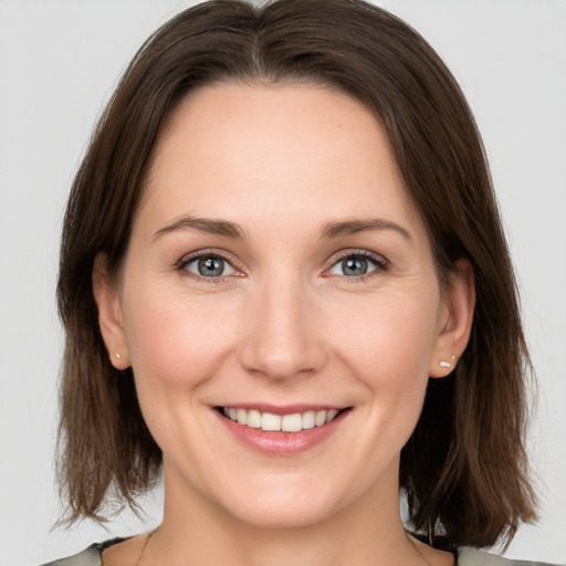 Joyful white young-adult female with medium  brown hair and grey eyes