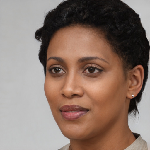 Joyful black young-adult female with short  black hair and brown eyes