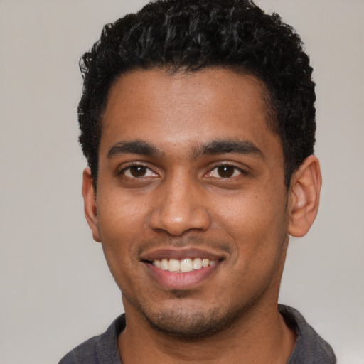 Joyful black young-adult male with short  black hair and brown eyes