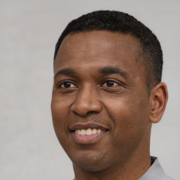 Joyful black young-adult male with short  black hair and brown eyes