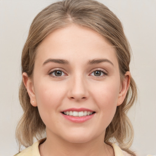 Joyful white young-adult female with medium  brown hair and grey eyes