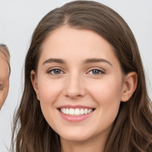 Joyful white young-adult female with long  brown hair and brown eyes