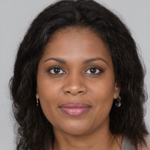 Joyful black young-adult female with long  brown hair and brown eyes