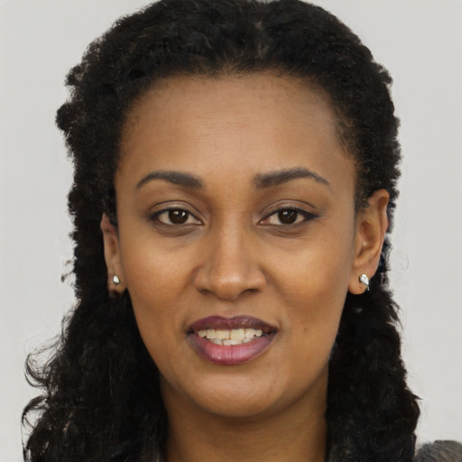 Joyful black young-adult female with long  black hair and brown eyes