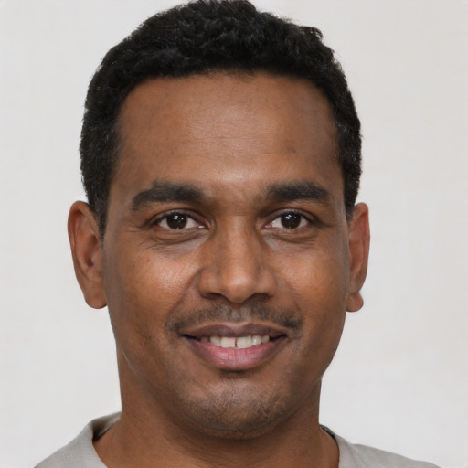 Joyful black young-adult male with short  black hair and brown eyes
