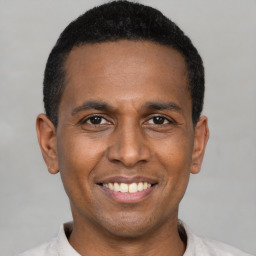 Joyful latino young-adult male with short  black hair and brown eyes