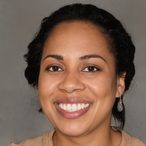 Joyful black adult female with long  brown hair and brown eyes