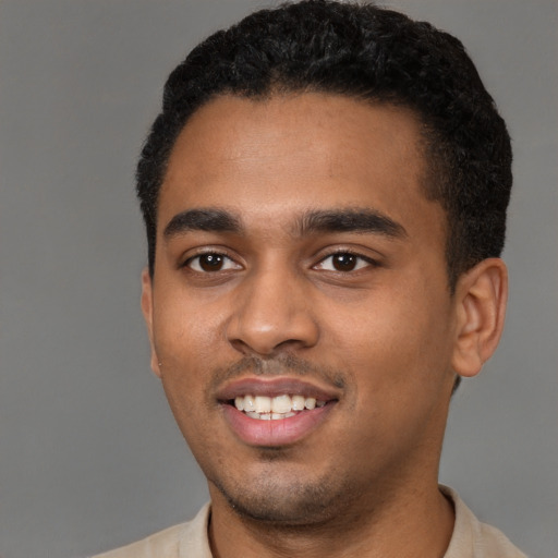 Joyful black young-adult male with short  black hair and brown eyes