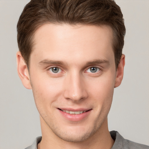 Joyful white young-adult male with short  brown hair and grey eyes