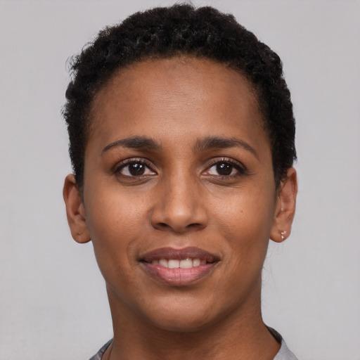 Joyful black young-adult female with short  black hair and brown eyes