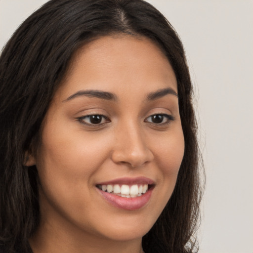 Joyful latino young-adult female with long  brown hair and brown eyes