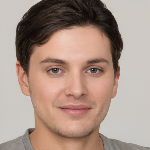 Joyful white young-adult male with short  brown hair and grey eyes