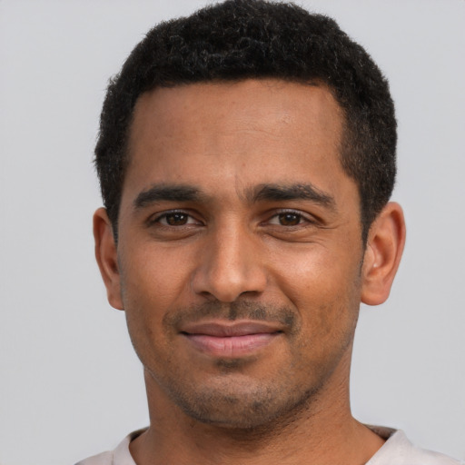 Joyful black young-adult male with short  black hair and brown eyes