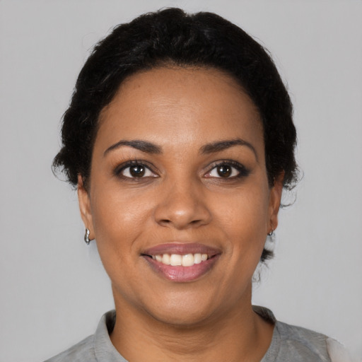 Joyful black young-adult female with short  black hair and brown eyes