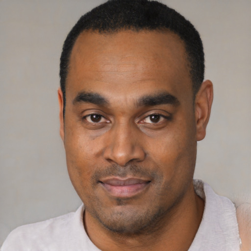 Joyful black young-adult male with short  black hair and brown eyes