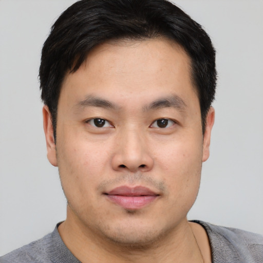 Joyful asian young-adult male with short  black hair and brown eyes