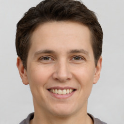 Joyful white young-adult male with short  brown hair and grey eyes