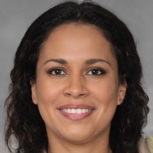 Joyful black young-adult female with long  brown hair and brown eyes