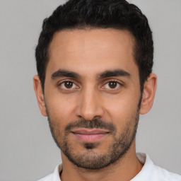 Joyful latino young-adult male with short  black hair and brown eyes