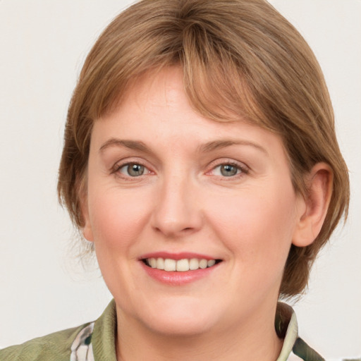 Joyful white young-adult female with medium  brown hair and grey eyes