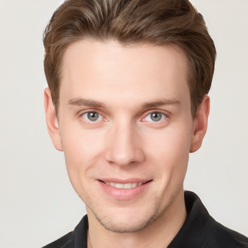 Joyful white young-adult male with short  brown hair and grey eyes