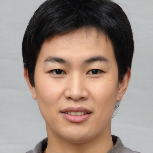 Joyful asian young-adult male with short  black hair and brown eyes