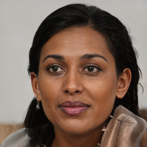 Joyful black young-adult female with long  brown hair and brown eyes