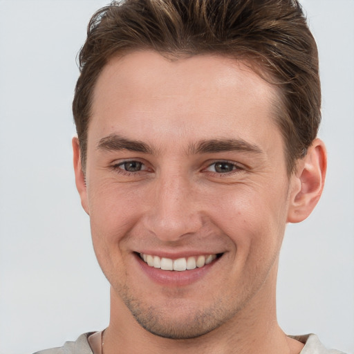 Joyful white young-adult male with short  brown hair and grey eyes