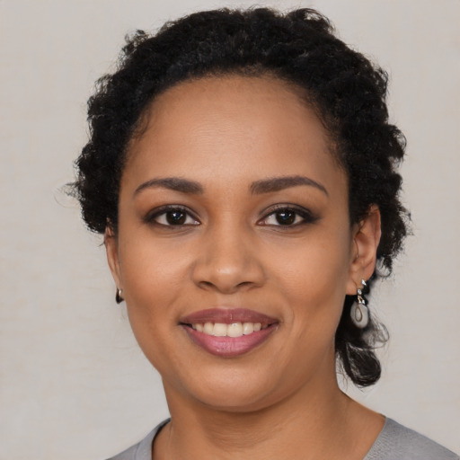 Joyful black young-adult female with short  black hair and brown eyes