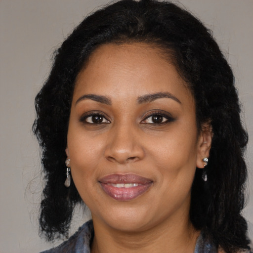 Joyful black young-adult female with long  brown hair and brown eyes