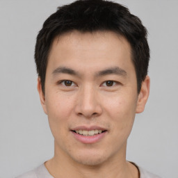 Joyful asian young-adult male with short  brown hair and brown eyes